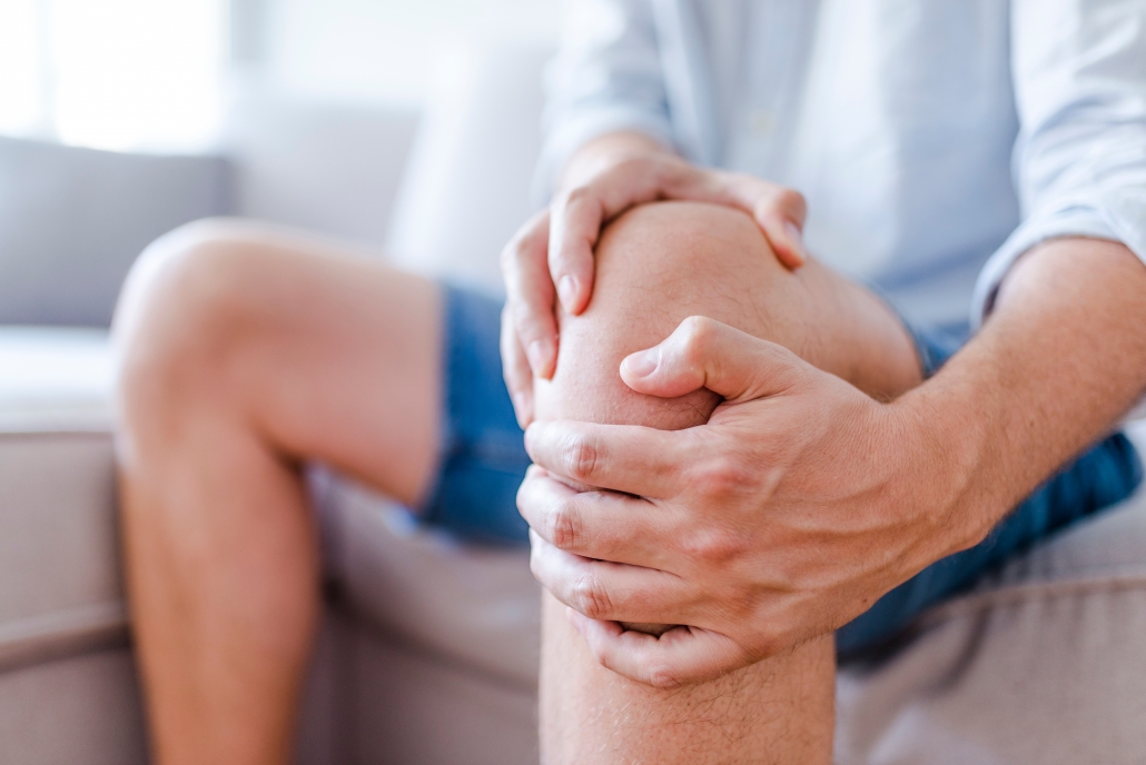 Image depicting knee pain patient holding knee.